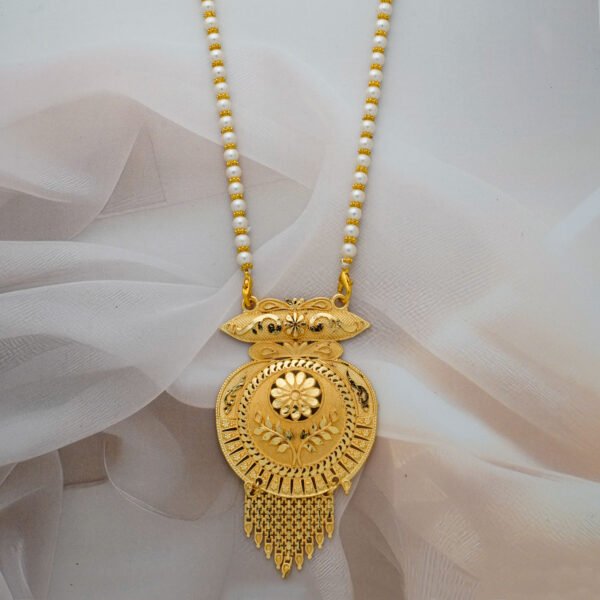 A long gold-tone necklace with a chain made of pearls and gold beads, suspending a large, ornate pendant with a circular floral motif and hanging chain tassels